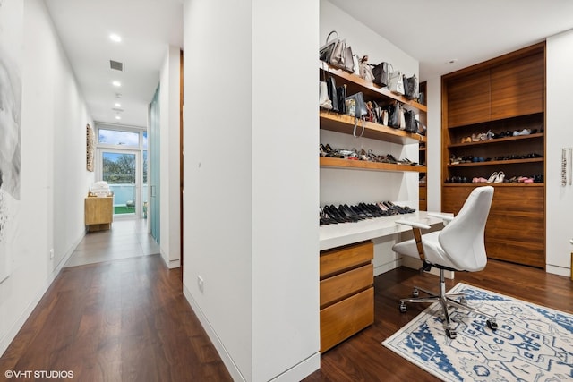 office area with visible vents, baseboards, dark wood-style floors, and built in desk