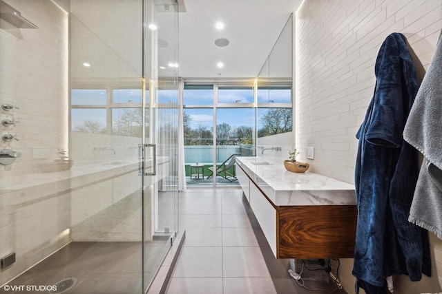 full bathroom featuring a sink, expansive windows, a shower stall, and tile patterned flooring