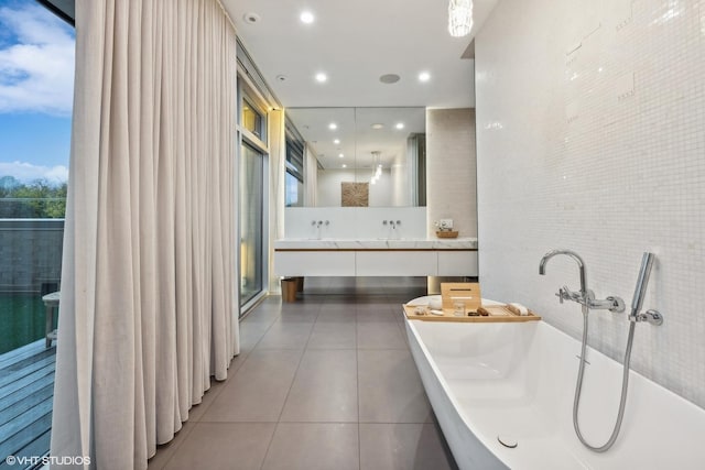 full bathroom with tile patterned flooring, double vanity, recessed lighting, a soaking tub, and a sink