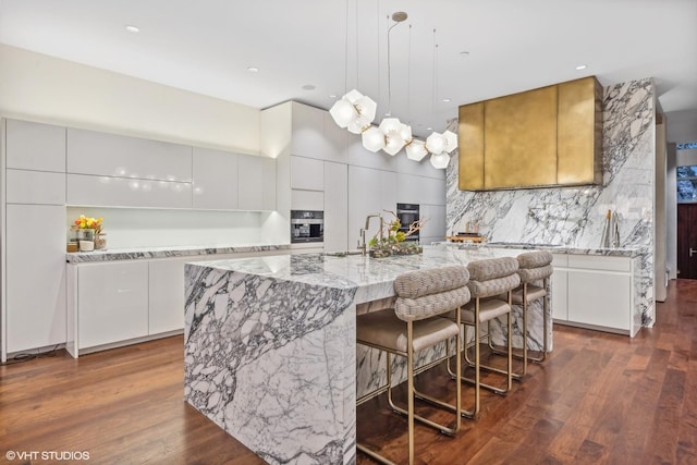 kitchen featuring dark wood-type flooring, light stone counters, modern cabinets, and backsplash