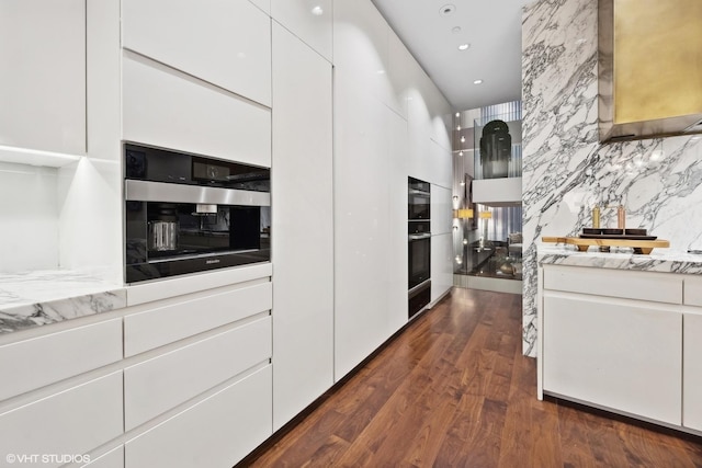 kitchen featuring dark wood finished floors, decorative backsplash, recessed lighting, a towering ceiling, and white cabinetry