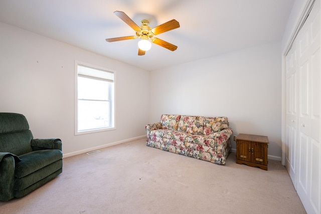 living area featuring light carpet and ceiling fan