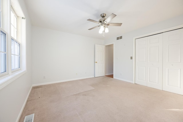 unfurnished bedroom featuring a closet, ceiling fan, and light colored carpet