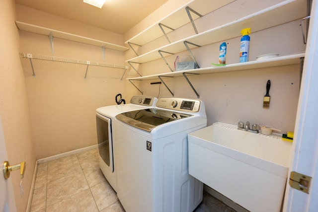 clothes washing area featuring sink, light tile patterned flooring, and separate washer and dryer