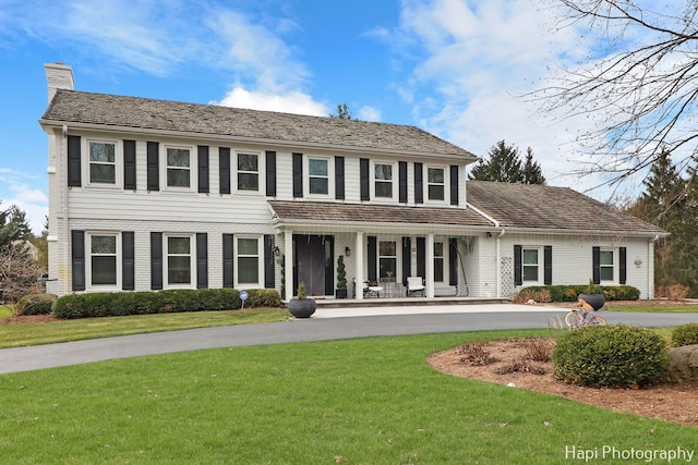 colonial-style house with a porch and a front lawn