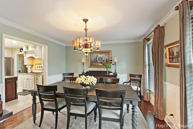 dining area with ornamental molding, wood-type flooring, and a chandelier