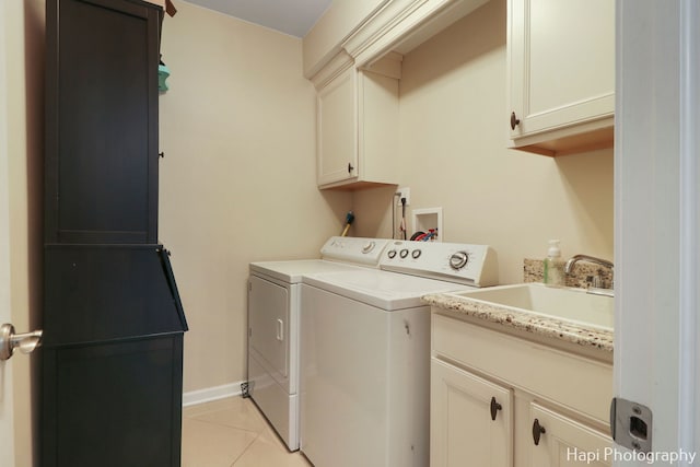 washroom with sink, cabinets, washing machine and clothes dryer, and light tile patterned flooring