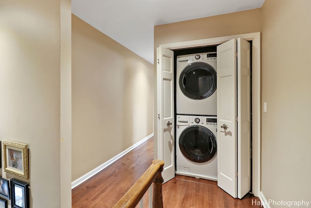 laundry room with hardwood / wood-style flooring and stacked washer and clothes dryer