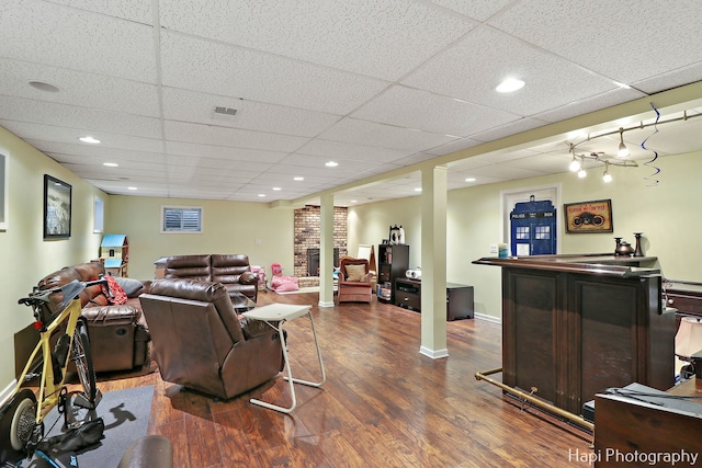 living room with dark hardwood / wood-style flooring, a drop ceiling, and indoor bar