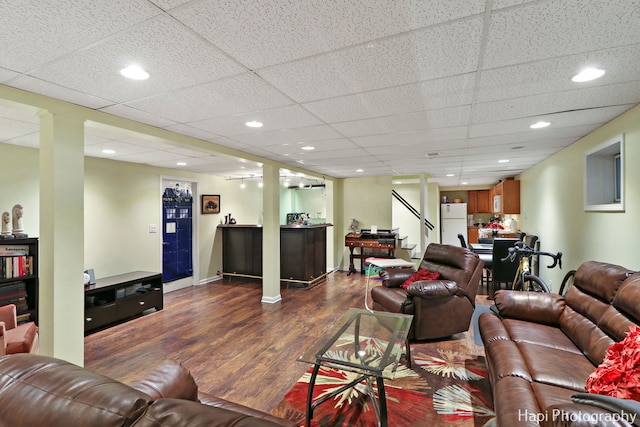 living room featuring a paneled ceiling, dark wood-type flooring, and bar