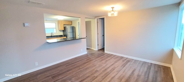 unfurnished living room with hardwood / wood-style floors and a notable chandelier