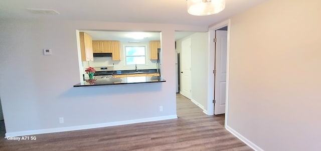 kitchen with light brown cabinetry, sink, white stove, and hardwood / wood-style flooring