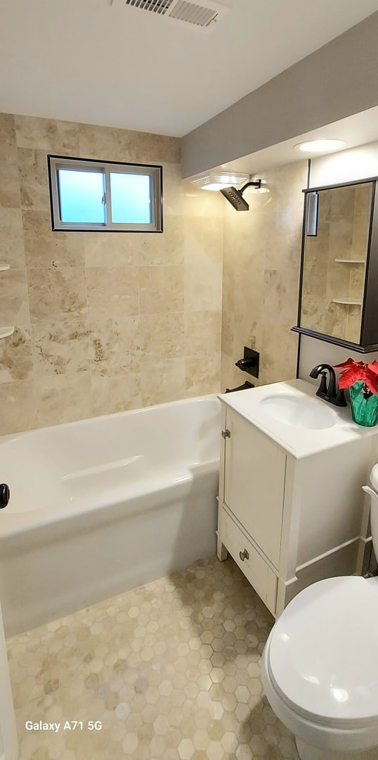 full bathroom featuring vanity, toilet, and tiled shower / bath