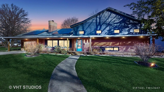 view of front of property featuring solar panels and a yard