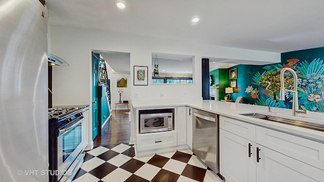 kitchen with kitchen peninsula, appliances with stainless steel finishes, dark wood-type flooring, sink, and white cabinetry