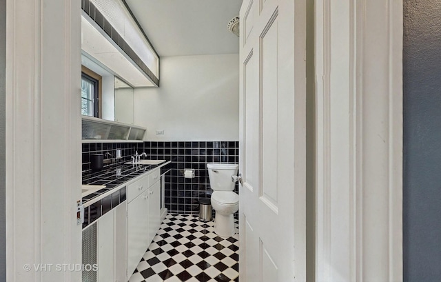 bathroom with vanity, tile walls, and toilet