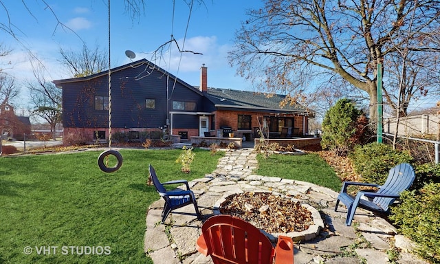 rear view of house with a patio area, a yard, and an outdoor fire pit