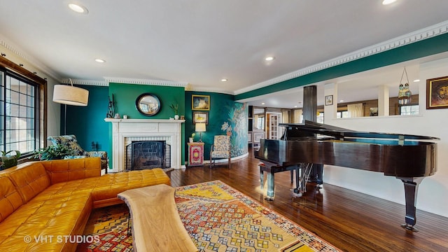 living room with crown molding, wood-type flooring, and a brick fireplace