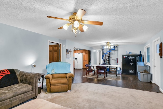 living room featuring dark hardwood / wood-style floors, ceiling fan, and a textured ceiling