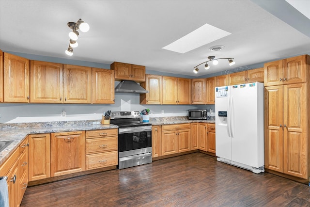 kitchen with a skylight, light stone countertops, wall chimney exhaust hood, stainless steel appliances, and dark hardwood / wood-style floors