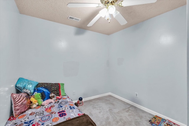 bedroom featuring ceiling fan, carpet floors, and a textured ceiling