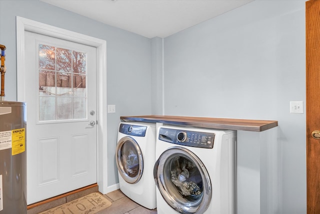 laundry area featuring washing machine and clothes dryer, light tile patterned floors, and water heater