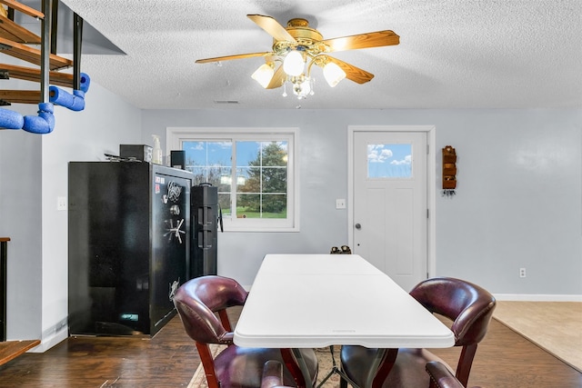 dining room featuring a textured ceiling, ceiling fan, and dark wood-type flooring