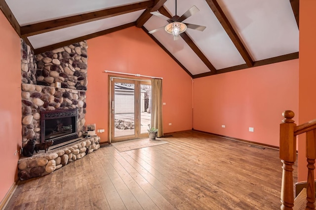 unfurnished living room with ceiling fan, lofted ceiling with beams, light hardwood / wood-style floors, and a fireplace