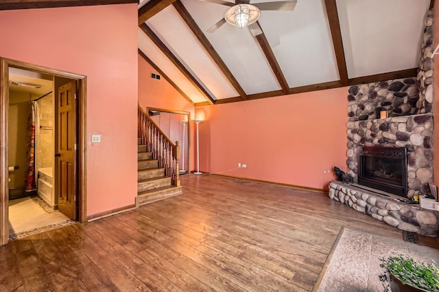 unfurnished living room with hardwood / wood-style floors, high vaulted ceiling, ceiling fan, a fireplace, and beam ceiling