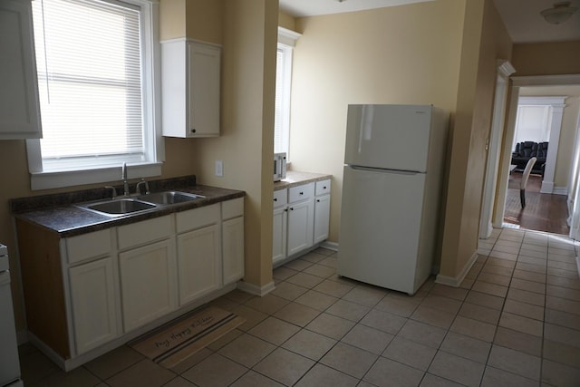 kitchen featuring white cabinetry, sink, white fridge, and light tile patterned floors