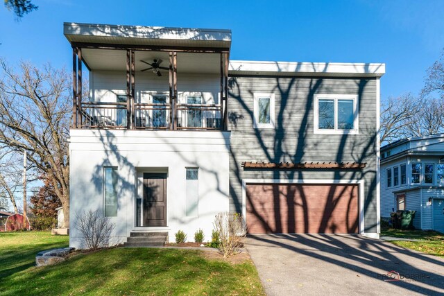 view of front facade featuring a balcony, a front yard, and a garage