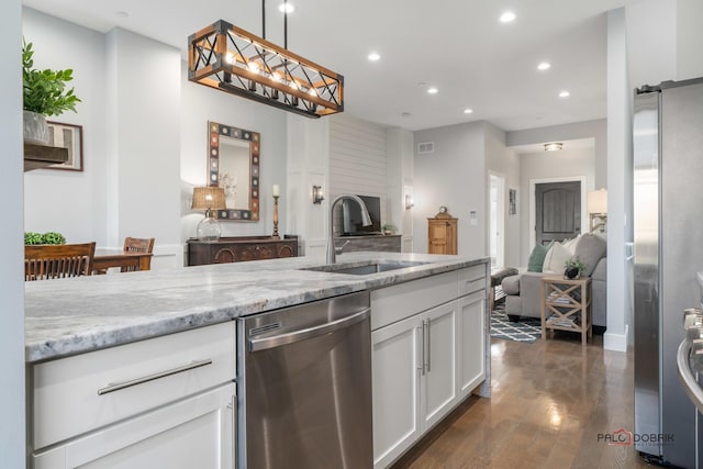 kitchen with sink, hanging light fixtures, light stone countertops, appliances with stainless steel finishes, and white cabinetry