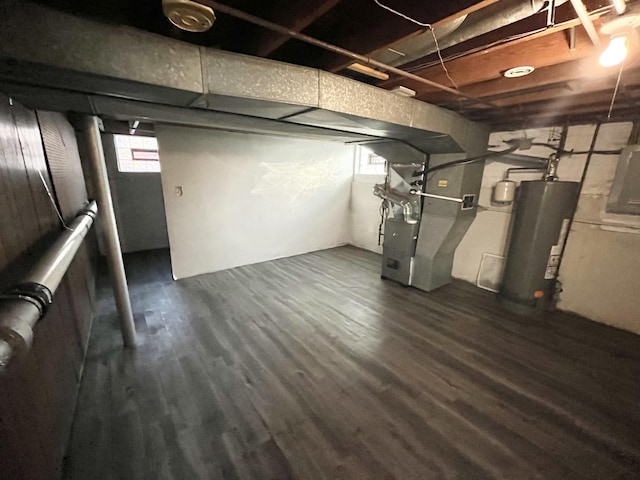 basement featuring heating unit, dark wood-type flooring, and gas water heater