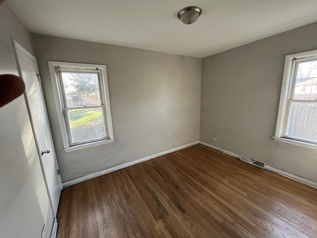 unfurnished room with a wealth of natural light and dark wood-type flooring