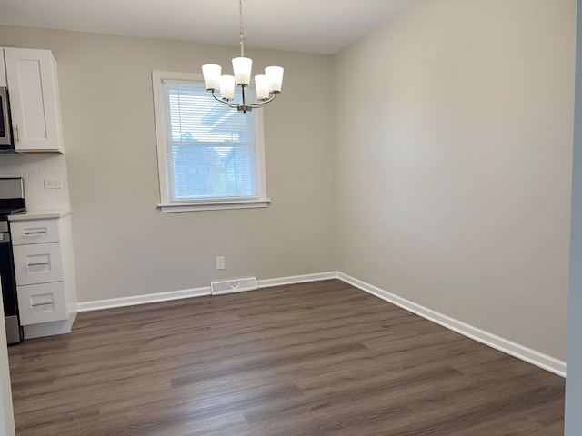 unfurnished dining area featuring an inviting chandelier and dark wood-type flooring