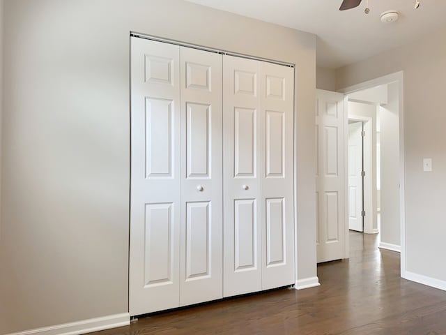 unfurnished bedroom with a closet, dark hardwood / wood-style flooring, and ceiling fan