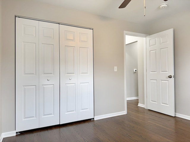 unfurnished bedroom featuring ceiling fan, a closet, and dark wood-type flooring