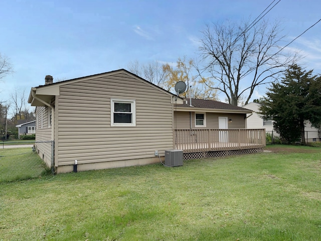 rear view of property featuring central AC, a deck, and a lawn