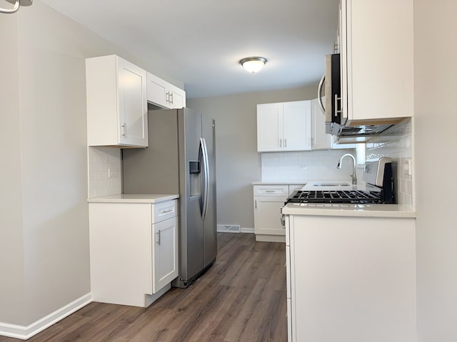 kitchen featuring white cabinets, tasteful backsplash, dark wood-type flooring, and stainless steel appliances