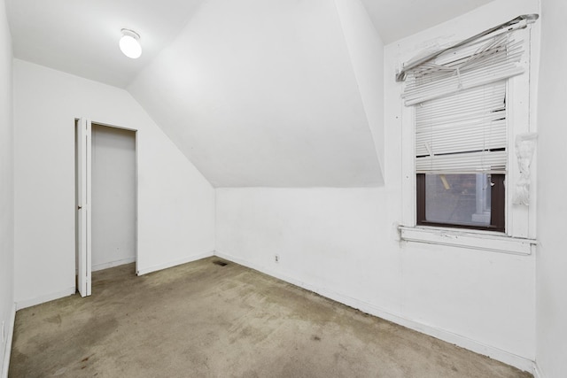 additional living space with light colored carpet and vaulted ceiling