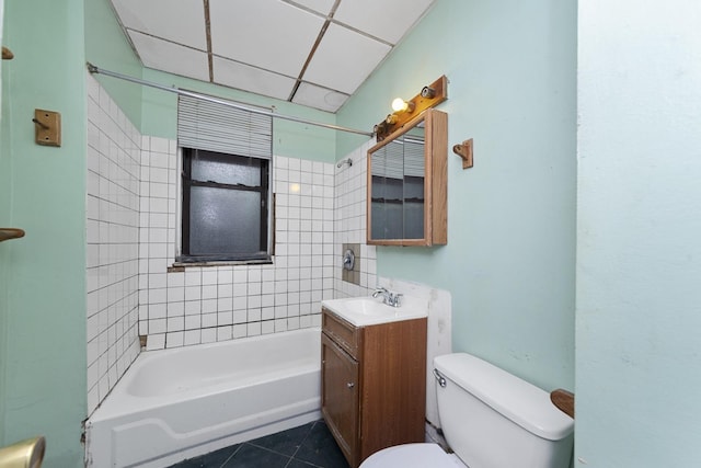 full bathroom featuring a drop ceiling, vanity, tile patterned floors, tiled shower / bath, and toilet