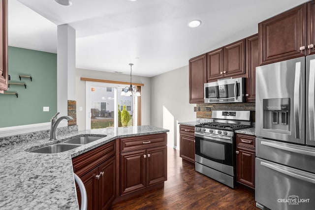 kitchen featuring light stone countertops, stainless steel appliances, dark hardwood / wood-style flooring, a notable chandelier, and decorative light fixtures