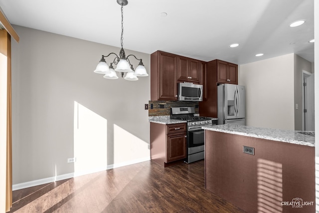 kitchen featuring an inviting chandelier, light stone counters, dark hardwood / wood-style floors, pendant lighting, and appliances with stainless steel finishes