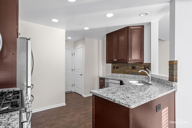 kitchen with sink, dark hardwood / wood-style floors, decorative backsplash, light stone countertops, and appliances with stainless steel finishes