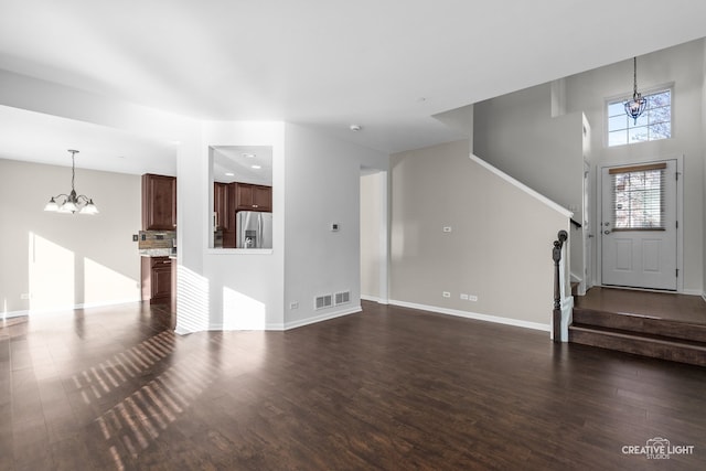 unfurnished living room with dark hardwood / wood-style flooring and an inviting chandelier