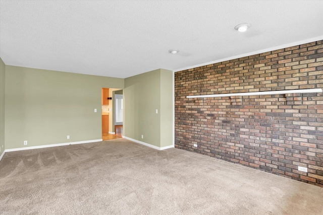 empty room featuring carpet, brick wall, and a textured ceiling