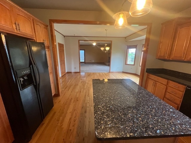 kitchen with decorative light fixtures, light hardwood / wood-style floors, black fridge with ice dispenser, and dark stone countertops