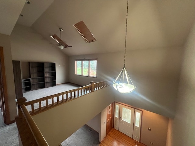 stairs featuring ceiling fan, wood-type flooring, and high vaulted ceiling