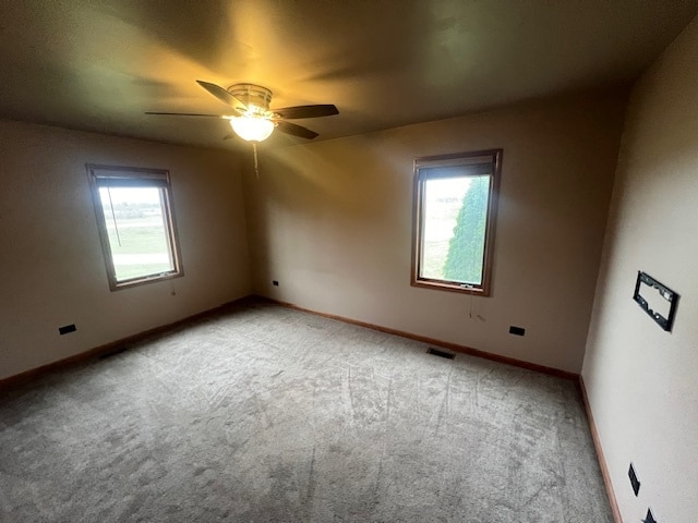 unfurnished room with ceiling fan, light colored carpet, and a healthy amount of sunlight