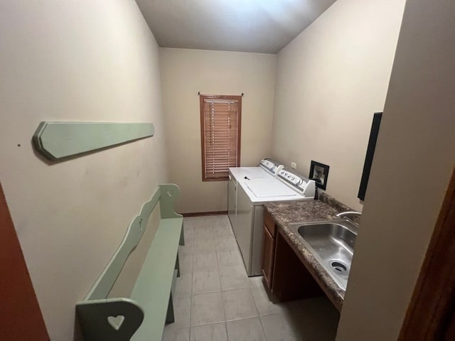 clothes washing area with light tile patterned floors, washer and clothes dryer, and sink